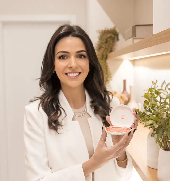 Dra. Bruna Rabaioli segurando um alinhador Invisalign, destacando o produto durante uma consulta.